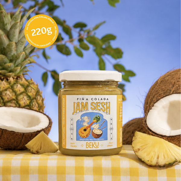 Beku Pina Colada Jam Sesh fruit spread jar, 220 g, with pineapple and halved coconuts on a yellow gingham tablecloth