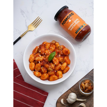 Bowl of gnocchi coated in Roasted Garlic and Tomato sauce, jar beside it