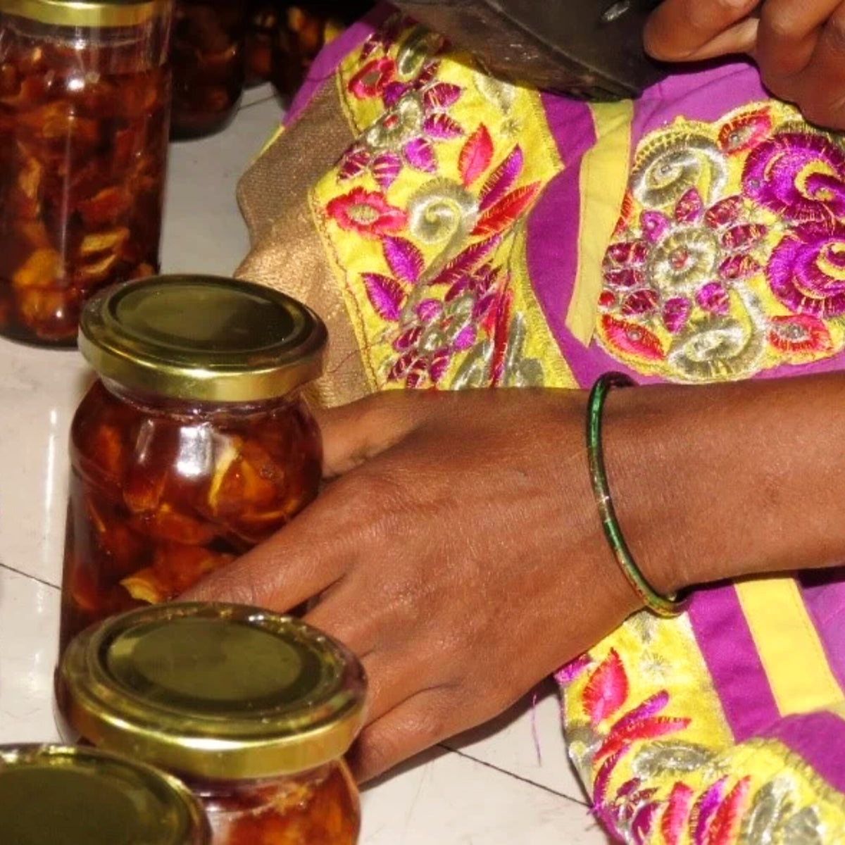 Hands filling pickle into jars at the Bangalapadigai centre