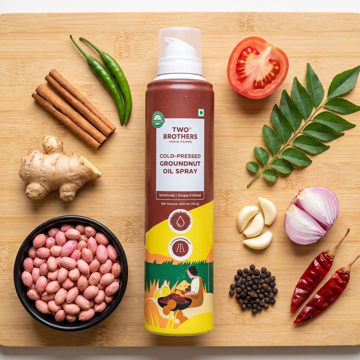 Groundnut oil spray can on a bamboo board with groundnuts, ginger, cinnamon, chillies, garlic, shallot and peppercorns