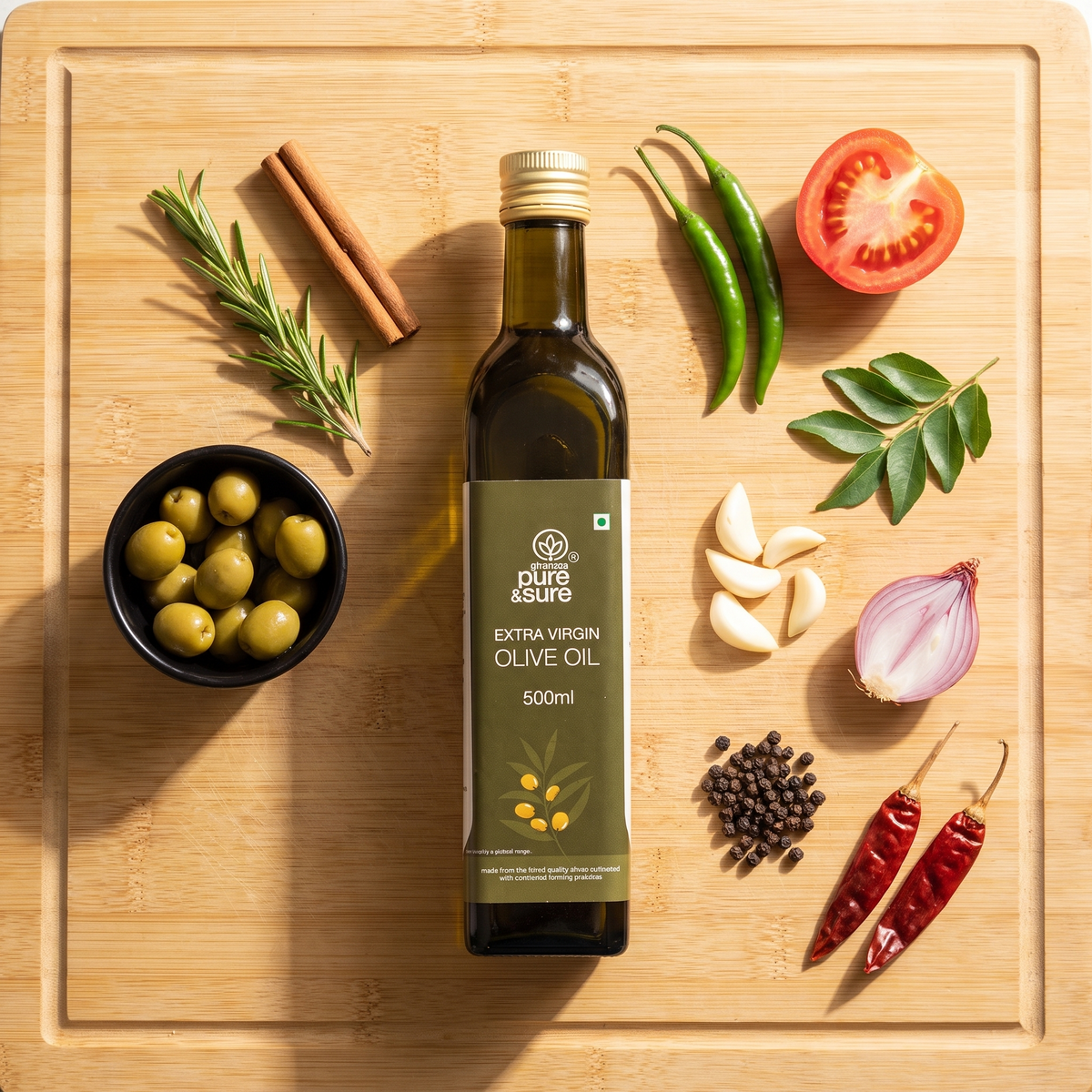 Extra virgin olive oil bottle on a bamboo board with olives, rosemary, cinnamon, chillies, garlic, shallot and peppercorns