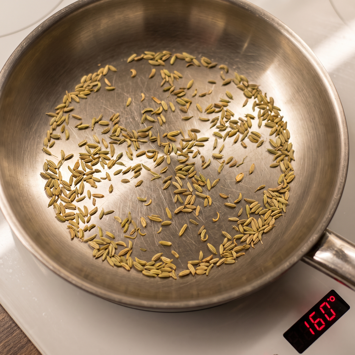 Fennel seeds dry-roasting in a steel pan