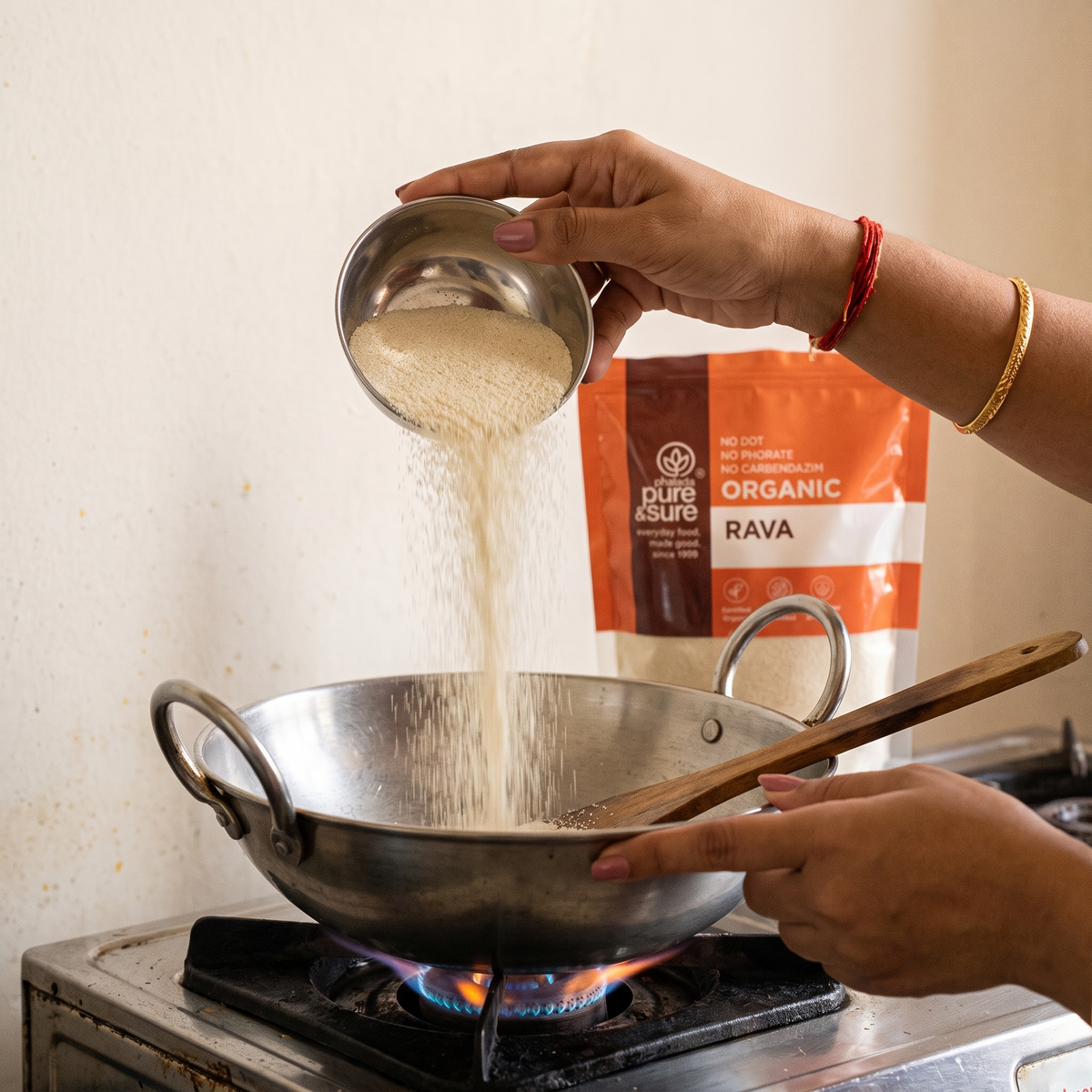 Pouring rava into a hot kadai from a steel bowl, with the pack behind