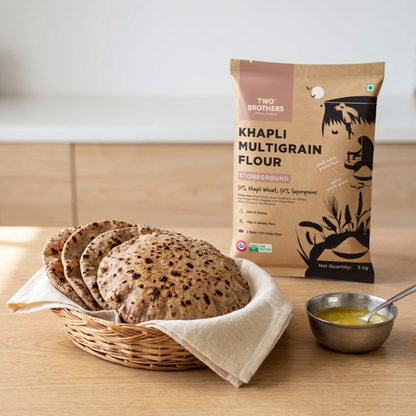 Fresh multigrain rotis stacked in a cloth-lined basket with the Khapli Multigrain Atta pack behind
