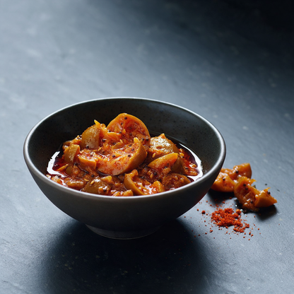 Traditional South Indian lime pickle in a dark stoneware bowl, cured in mustard oil with whole mustard and fenugreek seeds