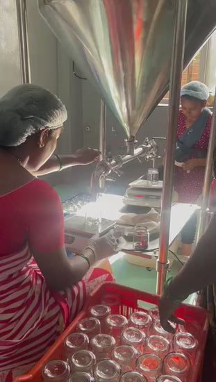 Video of the Beku jam kitchen, with workers filling rows of glass jars from a stainless steel filling machine