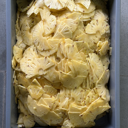 Fresh pineapple sliced thin in a tray at Smunchie, before drying